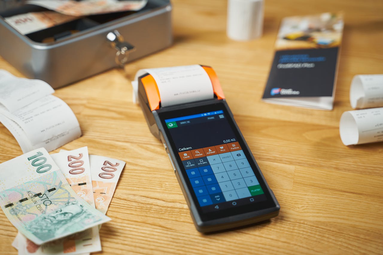 services-02 A modern digital payment terminal on a wooden desk with cash and receipts.