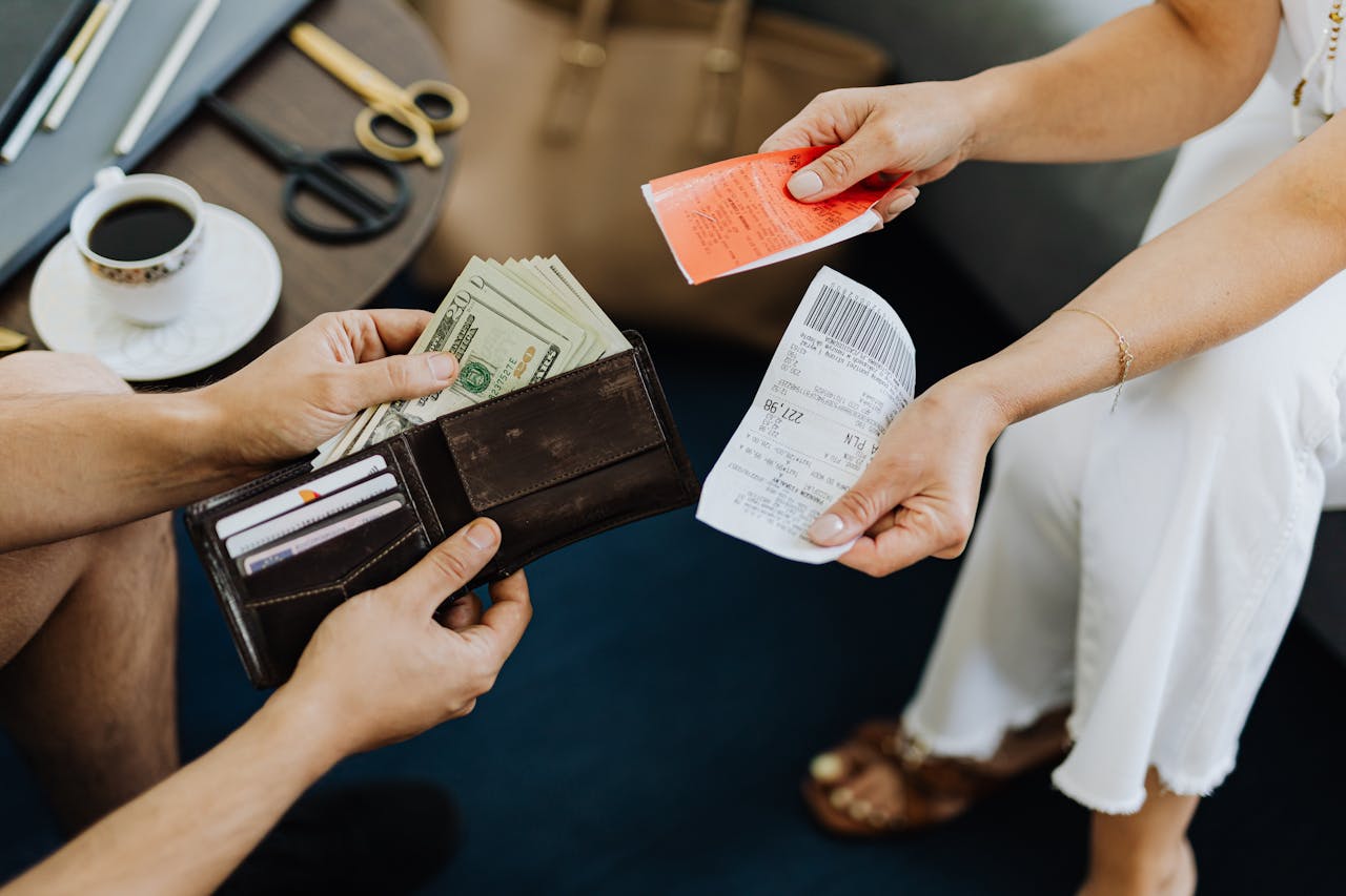 journey Close-up of a financial transaction involving cash and receipts over a coffee table.